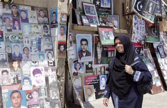 A Libyan woman walks past portraits of people killed or who have disappeared during the rule of Libyan leader Moammar Gadhafi's regime at the court square in the rebel-held capital Benghazi, Libya.